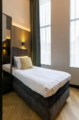 a bedroom with a large bed in a room with windows at Monument Hotel in Zaandam