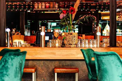 a wooden bar with two chairs and a vase of flowers at Monument Hotel in Zaandam
