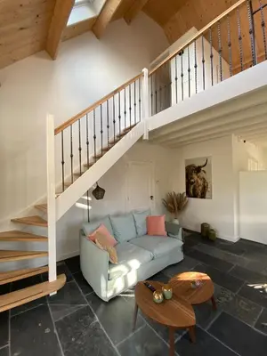 a living room with a blue couch and a staircase at B&B De Porrel in Polsbroek