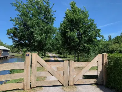 a wooden gate in front of a fence at B&B De Porrel in Polsbroek