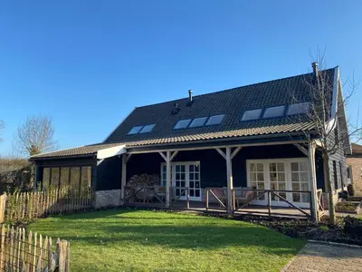 a house with a black roof and a yard at B&B De Porrel in Polsbroek