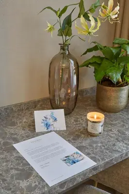 a table with a vase and a card and a candle at Breathe Boutique Hotel in Leiden