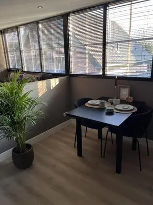 a blue table and chairs in a room with windows at B&B 'Op Eemdijk' in Eemdijk