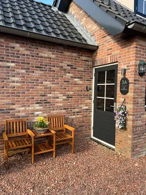 two chairs and a table in front of a brick building at B&B 'Op Eemdijk' in Eemdijk