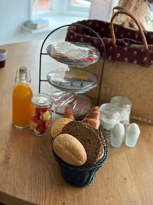 a basket of bread on a table with orange juice at B&B 'Op Eemdijk' in Eemdijk