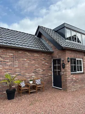 a brick house with two chairs and a table at B&B 'Op Eemdijk' in Eemdijk