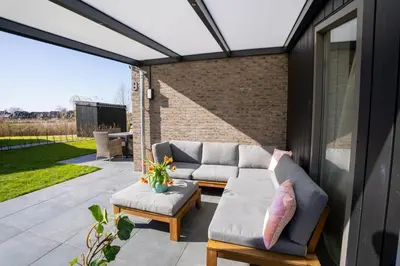 a patio with a couch and two ottoman at Meertje Villa 81 op Recreatiepark De Wielen in Sint Maarten