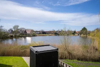 a black trash can sitting in front of a lake at Meertje Villa 81 op Recreatiepark De Wielen in Sint Maarten