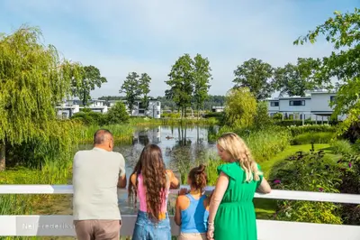 a family standing on a bridge looking at a pond at Comfort Rooms by EuroParcs Bad Hulckesteijn in Nijkerk