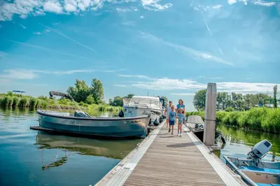 a group of people standing on a dock next to boats at Comfort Rooms by EuroParcs Bad Hulckesteijn in Nijkerk