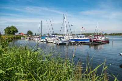 a group of boats docked at a dock in the water at Comfort Rooms by EuroParcs Bad Hulckesteijn in Nijkerk
