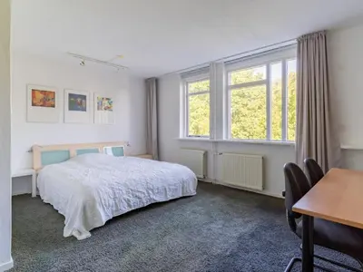 a bedroom with a bed and a desk and windows at Apartment in Alkmaar with sea beach in Alkmaar