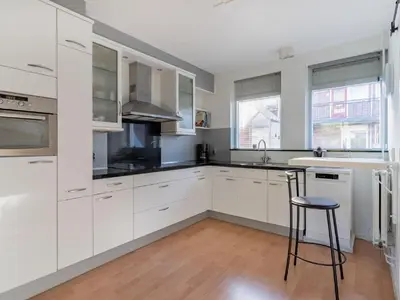 a white kitchen with white cabinets and a stool at Apartment in Alkmaar with sea beach in Alkmaar