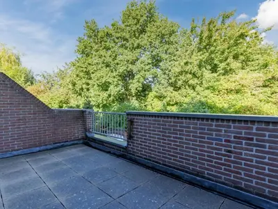a brick wall with a fence and trees in the background at Apartment in Alkmaar with sea beach in Alkmaar