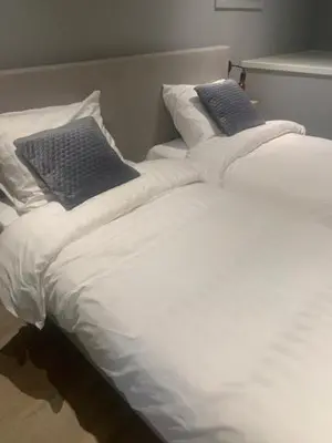 a white bed with two blue pillows on it at B en B Volendam in Volendam