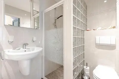 a white bathroom with a sink and a toilet at Casa Queensway in Zandvoort