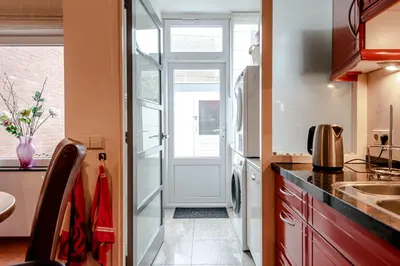 a kitchen with a refrigerator and a door with a sink at Casa Queensway in Zandvoort