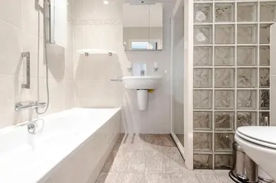 a white bathroom with a sink and a toilet at Casa Queensway in Zandvoort