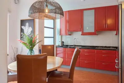 a kitchen with red cabinets and a wooden table at Casa Queensway in Zandvoort