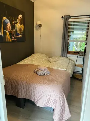 a bedroom with a bed and a painting on the wall at Het Zeepaardje in Dirkshorn