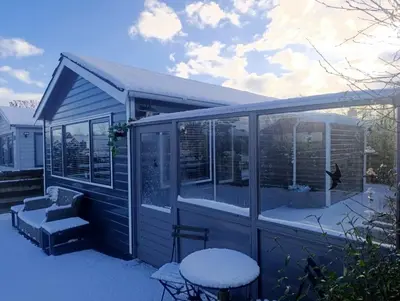 a screened in porch of a house with snow on it at Het Zeepaardje in Dirkshorn
