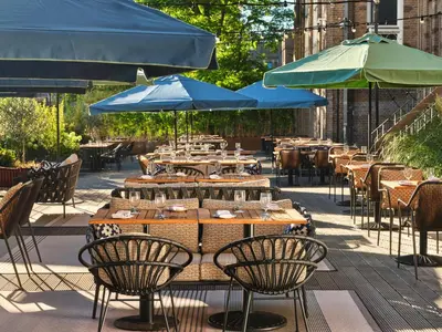 a row of tables with blue umbrellas on a patio at The Hoxton Lloyd Amsterdam City Centre East in Amsterdam