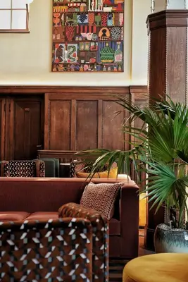 a living room with a couch and a painting on the wall at The Hoxton Lloyd Amsterdam City Centre East in Amsterdam