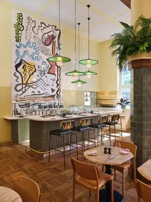 a restaurant with tables and chairs and a large mural at The Hoxton Lloyd Amsterdam City Centre East in Amsterdam