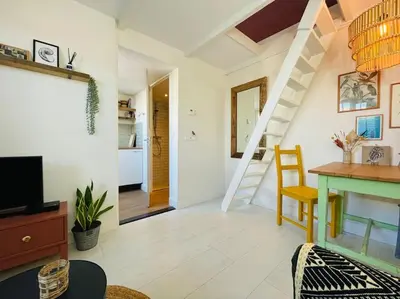 a living room with a staircase and a table at Have a nice stay! -The Birdhouse, Tiny home close to the beach in Noordwijk aan Zee
