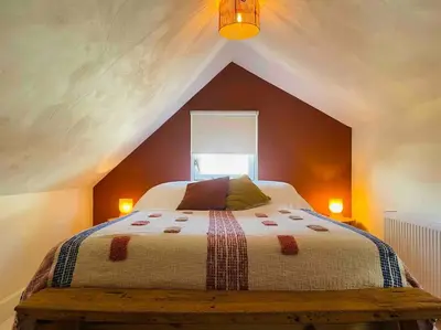 a bedroom with a large bed in a attic at Have a nice stay! -The Birdhouse, Tiny home close to the beach in Noordwijk aan Zee