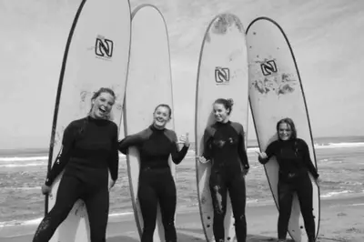 a group of four people standing on the beach with surfboards at Have a nice stay! -The Birdhouse, Tiny home close to the beach in Noordwijk aan Zee