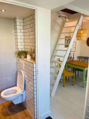 a bathroom with a toilet next to a staircase at Have a nice stay! -The Birdhouse, Tiny home close to the beach in Noordwijk aan Zee