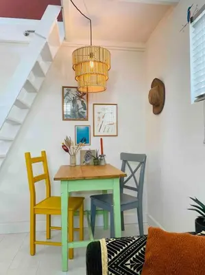 a table and chairs in a room with a staircase at Have a nice stay! -The Birdhouse, Tiny home close to the beach in Noordwijk aan Zee