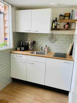 a kitchen with white cabinets and a sink at Have a nice stay! -The Birdhouse, Tiny home close to the beach in Noordwijk aan Zee