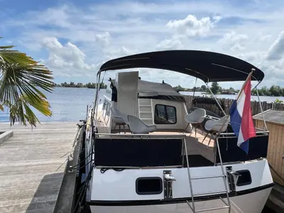 a boat tied up to a dock with a flag at NEW - LITTLE IBIZA, on a lake near Amsterdam, with HOT TUB! in Vinkeveen