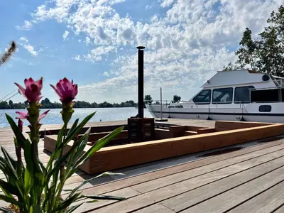 a boat is docked at a dock with a boat at NEW - LITTLE IBIZA, on a lake near Amsterdam, with HOT TUB! in Vinkeveen