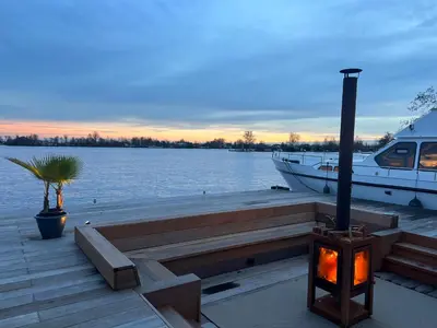 a dock with a boat and a palm tree and a boat at NEW - LITTLE IBIZA, on a lake near Amsterdam, with HOT TUB! in Vinkeveen