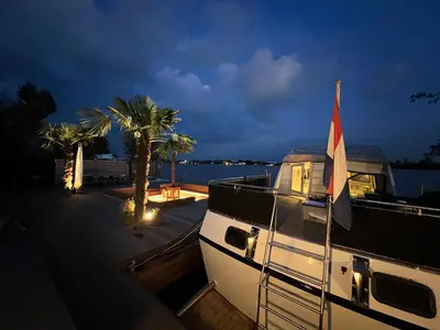 a boat with a flag on the deck at night at NEW - LITTLE IBIZA, on a lake near Amsterdam, with HOT TUB! in Vinkeveen
