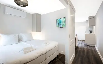 a white bedroom with a bed with white pillows at Finest Apartments in Haarlem