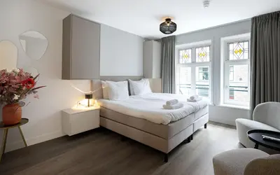 a bedroom with a bed and a couch and a chair at Finest Apartments in Haarlem
