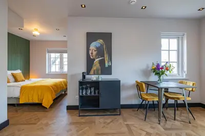 a bedroom with a bed and a table and a painting at Cottage Jacob in Zandvoort