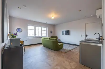 a living room with a green couch and a kitchen at Cottage Jacob in Zandvoort