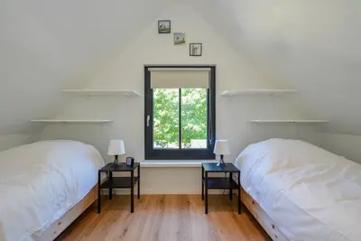 two beds in a room with a window at Villa Goudvink in Dirkshorn