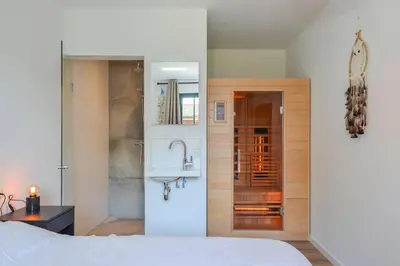 a bedroom with a bed and a sink and a bathroom at Villa Goudvink in Dirkshorn