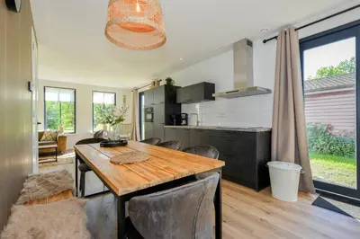 a kitchen and dining room with a wooden table and chairs at Villa Goudvink in Dirkshorn