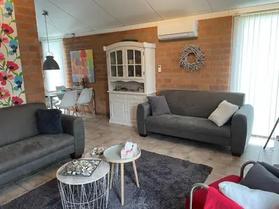 a living room with two couches and a table at NEU! Ferienhaus Zijper 24 in Burgerbrug