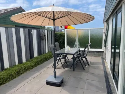 a table and chairs under an umbrella on a patio at NEU! Ferienhaus Zijper 24 in Burgerbrug