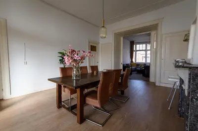 a dining room table with chairs and a vase of flowers at City House Hoorn in Hoorn