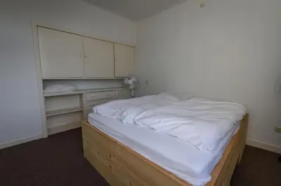 a bedroom with a bed with white sheets and cabinets at City House Hoorn in Hoorn