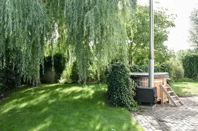 a garden with a hot tub under a tree at Spacious Comfort Villa Vera with hottub in Zeewolde
